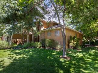 Nestled amidst lush greenery, this charming home offers a serene retreat with its stucco exterior and inviting facade.