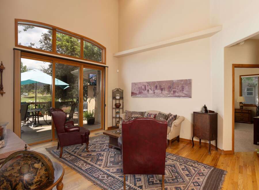 Step into this inviting living room featuring a soaring vaulted ceiling and a wall of windows that bathe the space in natural light.