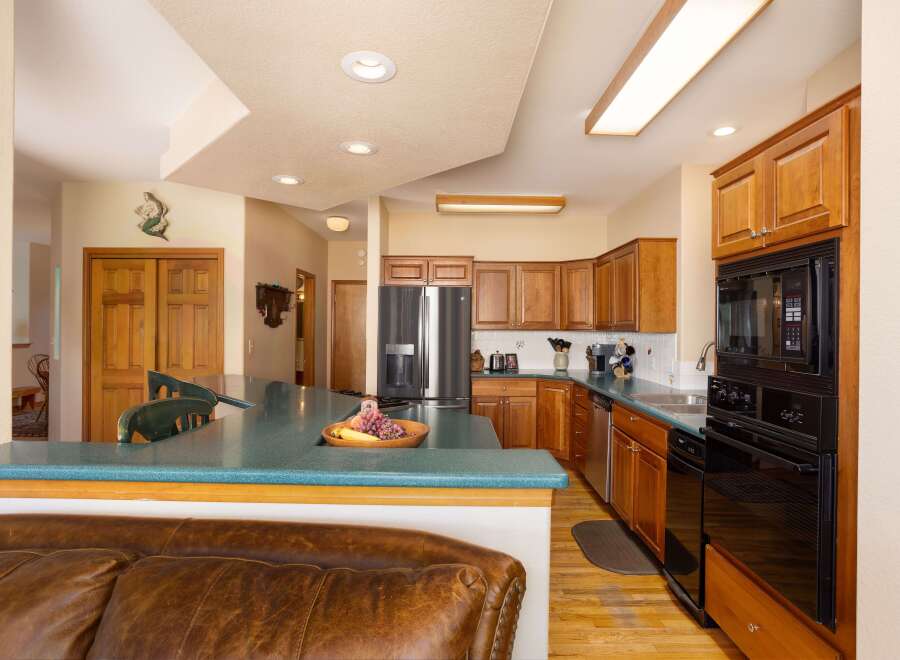 This spacious kitchen boasts beautiful cherry wood cabinets and a large island with a teal countertop, perfect for meal preparation and casual dining.