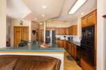 This spacious kitchen boasts beautiful cherry wood cabinets and a large island with a teal countertop, perfect for meal preparation and casual dining.
