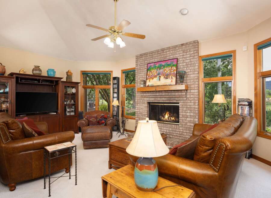 Cozy up by the brick fireplace in this inviting living room, featuring plush leather seating and a large entertainment center.