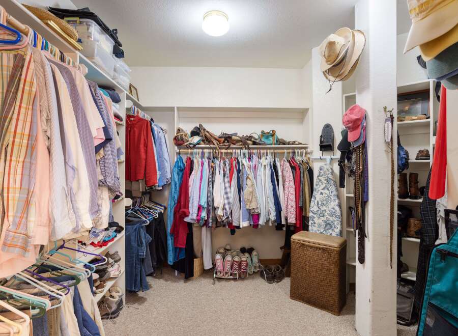 Discover ample storage in this spacious walk-in closet, featuring organized shelving and multiple hanging racks for all your clothing and accessories.