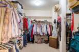 Discover ample storage in this spacious walk-in closet, featuring organized shelving and multiple hanging racks for all your clothing and accessories.
