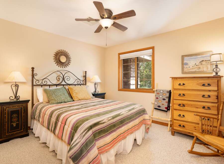 This charming bedroom features a comfortable queen-size bed with a colorful striped comforter and decorative pillows.