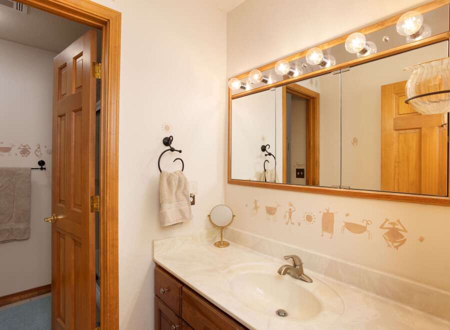Charming bathroom featuring a wooden vanity with a marble countertop and a white sink.