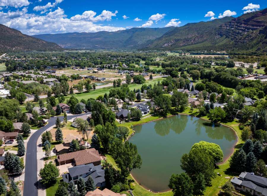 Discover this stunning aerial view of a picturesque suburban neighborhood nestled beside a serene lake and lush green golf course.