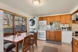 This charming kitchen offers a functional layout with ample wooden cabinetry and a mosaic tile backsplash.