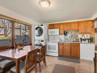 This charming kitchen offers a functional layout with ample wooden cabinetry and a mosaic tile backsplash.