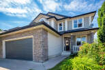 This stunning two-story home features a modern gray garage door and a welcoming front porch with stone accents.