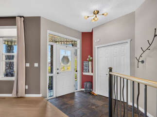 Step into this welcoming entryway featuring a bright white front door with decorative glass panels, perfect for letting in natural light.