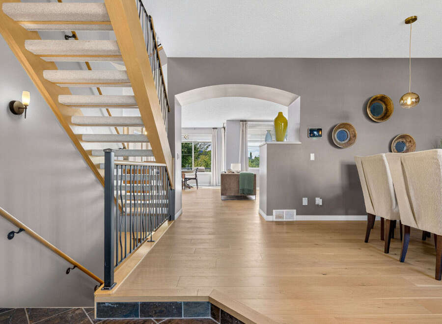 Step into this inviting entryway featuring a beautiful wooden staircase with carpeted treads and a sleek metal railing.