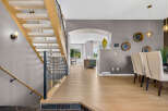 Step into this inviting entryway featuring a beautiful wooden staircase with carpeted treads and a sleek metal railing.