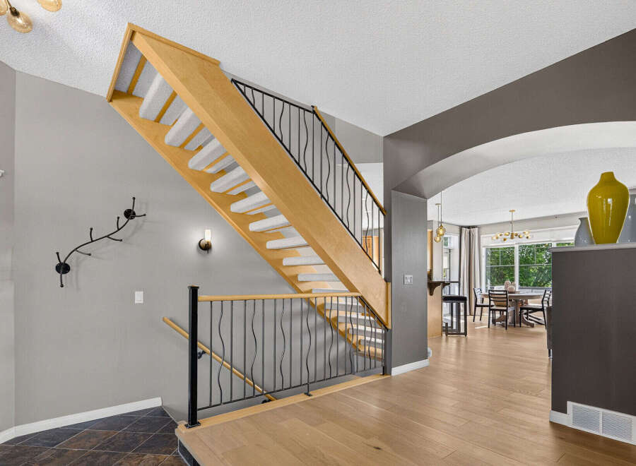 Step into this inviting home featuring a beautifully designed wooden staircase with elegant black railings, perfect for guiding you to the upper level.