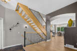 Step into this inviting home featuring a beautifully designed wooden staircase with elegant black railings, perfect for guiding you to the upper level.