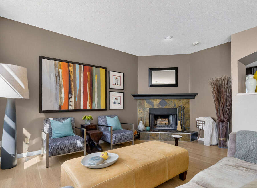 This inviting living room features a cozy fireplace with a stone surround and a sleek black mantel.