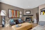 This inviting living room features a cozy fireplace with a stone surround and a sleek black mantel.