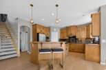 This spacious kitchen boasts beautiful natural wood cabinetry, a large island with seating, and a sleek stainless steel refrigerator.
