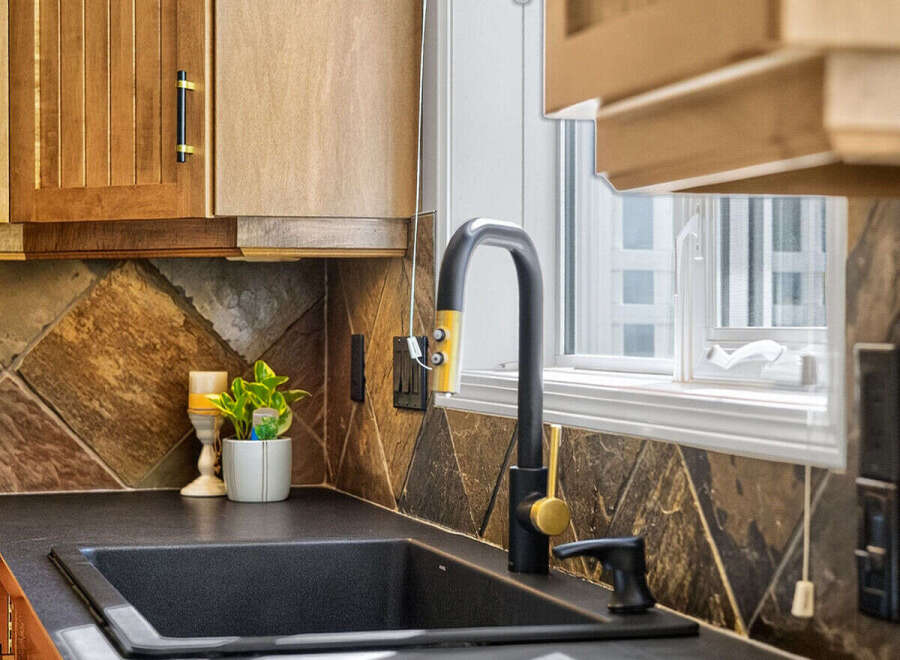 This kitchen features a sleek black sink and a modern black faucet with gold accents, complemented by warm wood cabinetry.