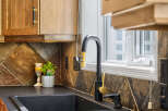 This kitchen features a sleek black sink and a modern black faucet with gold accents, complemented by warm wood cabinetry.