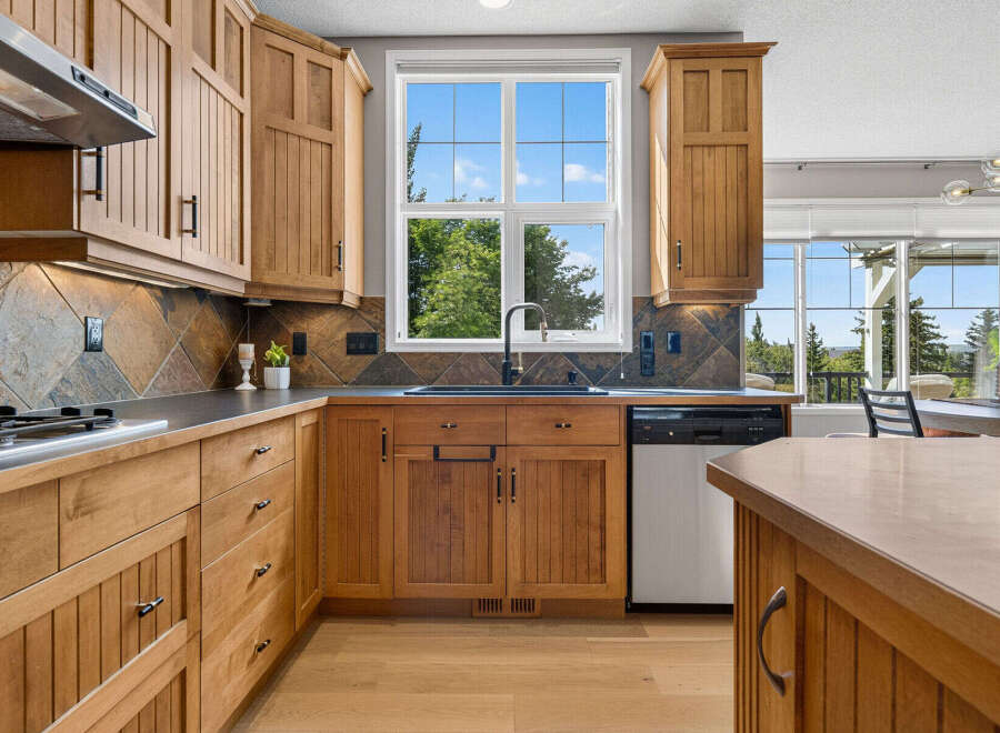 This beautifully appointed kitchen features custom wood cabinetry and a striking slate tile backsplash.