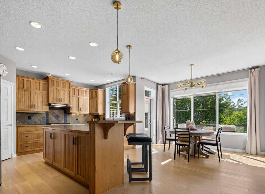 This spacious kitchen boasts beautiful natural wood cabinetry and a large island with seating, perfect for casual dining or entertaining.
