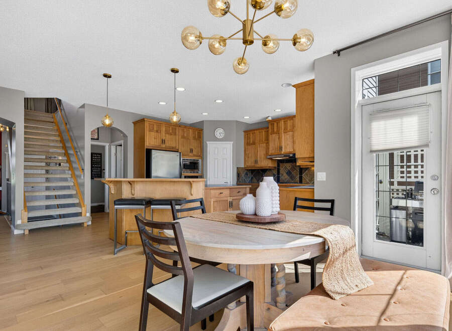 This spacious open-concept kitchen and dining area features warm wood cabinetry, a large island with seating, and a stylish chandelier.