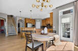 This spacious open-concept kitchen and dining area features warm wood cabinetry, a large island with seating, and a stylish chandelier.