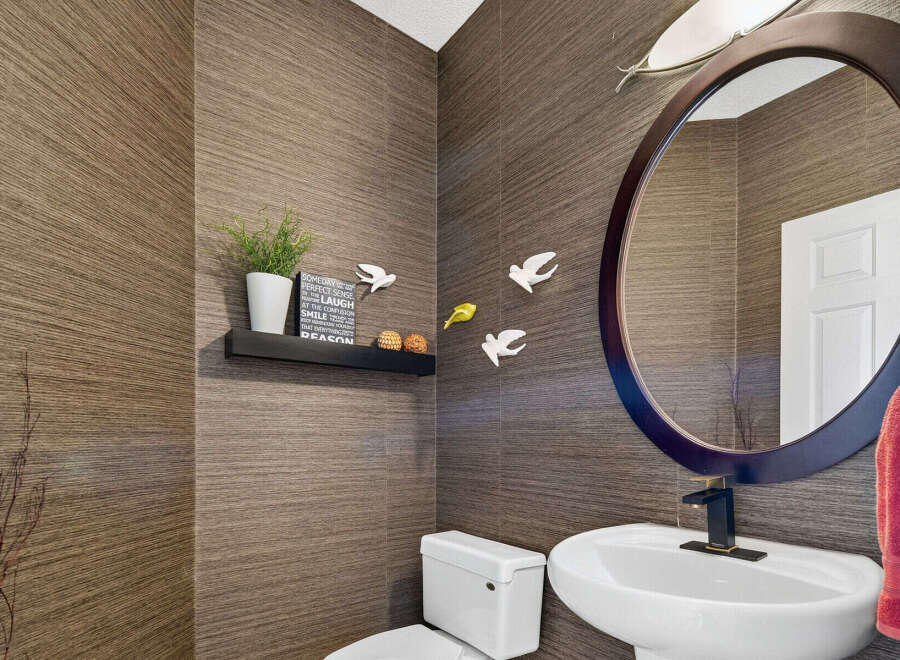 This stylish powder room features a unique textured wallpaper in a warm brown tone, creating a sophisticated and inviting atmosphere.