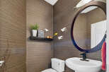 This stylish powder room features a unique textured wallpaper in a warm brown tone, creating a sophisticated and inviting atmosphere.
