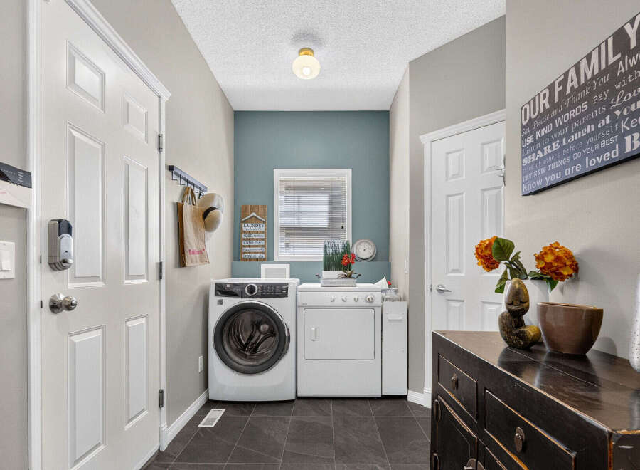 Discover the convenience of this functional laundry room, featuring a stacked washer and dryer set perfect for maximizing space.