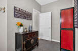 Welcome guests into a warm and inviting entryway featuring a charming 'Our Family Rules' sign, a decorative black cabinet with floral accents, and a striking red and black accent cabinet.
