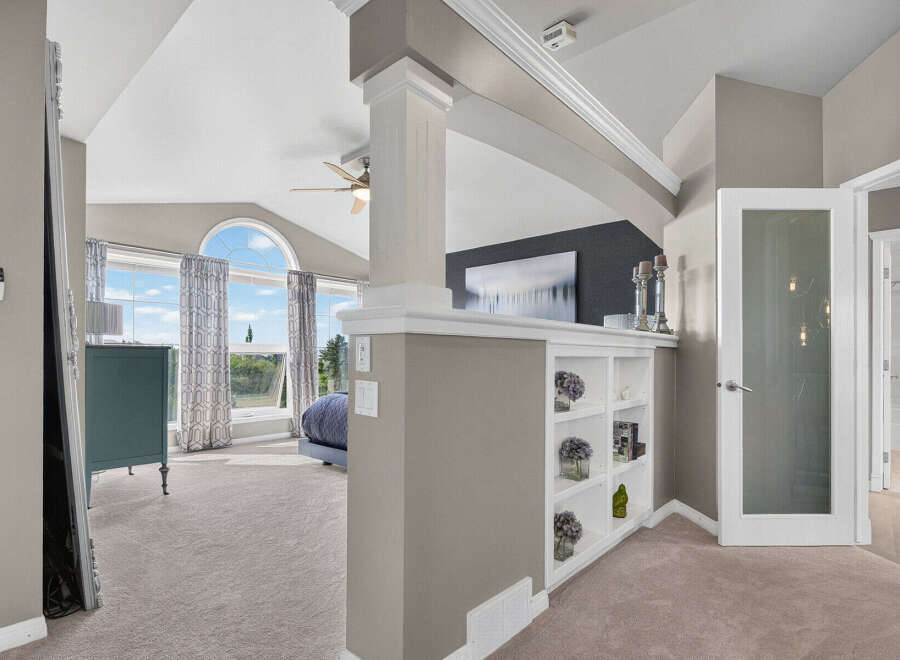 Experience luxury and comfort in this spacious master suite, featuring a vaulted ceiling and a large arched window that floods the room with natural light.