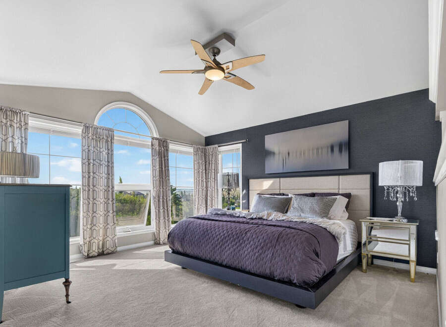 Experience luxury in this stunning master suite, featuring a vaulted ceiling and a large arched window that floods the room with natural light.
