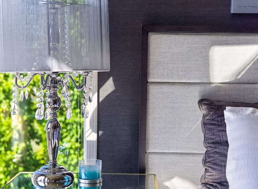 This bedroom features a luxurious mirrored nightstand with a crystal-embellished lamp, creating an elegant ambiance.