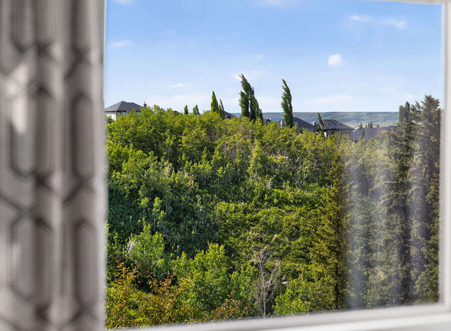 Enjoy the serene views from this property, offering a lush green landscape dotted with mature trees and glimpses of charming homes.