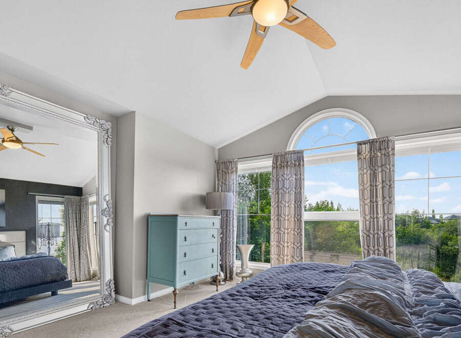 This spacious bedroom features a vaulted ceiling with a modern ceiling fan, perfect for maintaining a comfortable atmosphere.