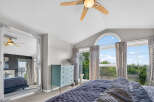 This spacious bedroom features a vaulted ceiling with a modern ceiling fan, perfect for maintaining a comfortable atmosphere.