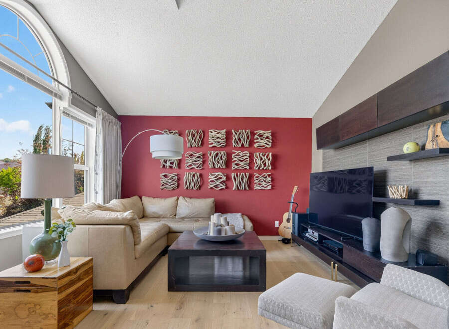 This living room boasts a striking red accent wall adorned with unique textured art pieces, creating a vibrant focal point.
