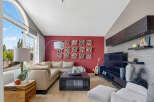 This living room boasts a striking red accent wall adorned with unique textured art pieces, creating a vibrant focal point.