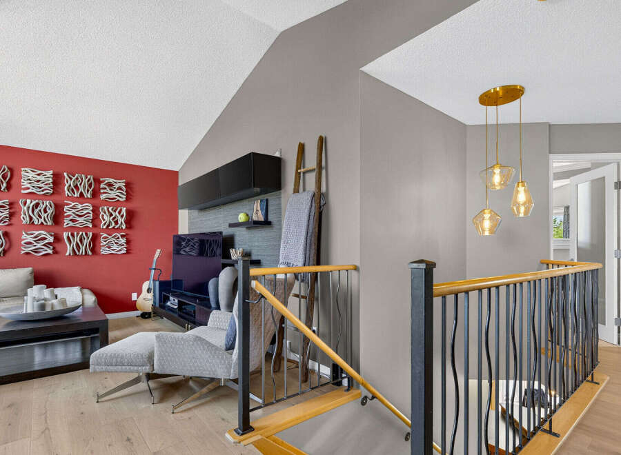 This stunning living area boasts a vibrant red accent wall adorned with unique decorative art pieces, complemented by a comfortable sectional sofa and a modern entertainment center.
