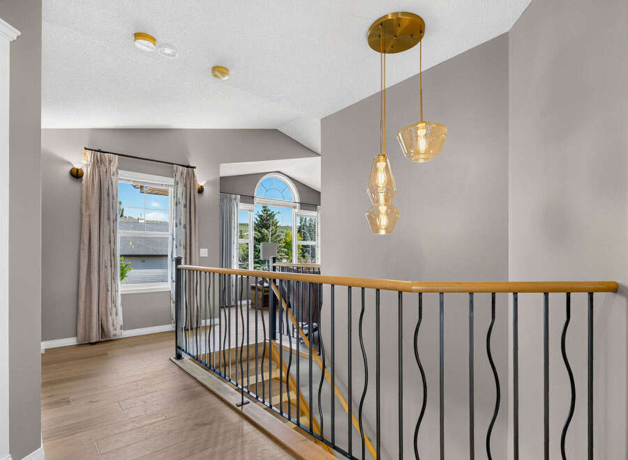 This spacious hallway features a modern aesthetic with elegant light fixtures and a sleek railing overlooking the staircase.