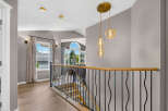 This spacious hallway features a modern aesthetic with elegant light fixtures and a sleek railing overlooking the staircase.