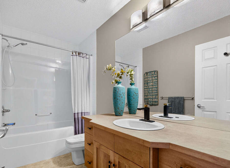 This bright and clean bathroom features a spacious bathtub with a shower and a white curtain.
