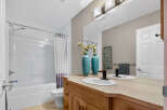This bright and clean bathroom features a spacious bathtub with a shower and a white curtain.