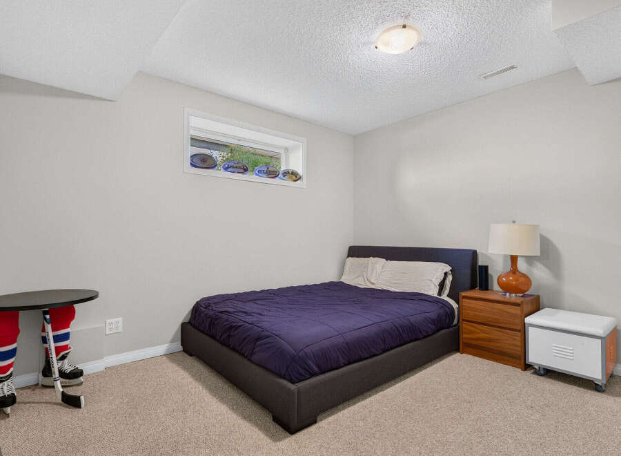 This charming bedroom features a comfortable queen-size bed with a deep purple comforter, perfect for a restful night's sleep.