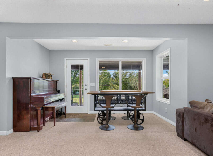 This inviting space features a classic upright piano, perfect for musical enjoyment, adjacent to a glass-paned door leading outdoors.