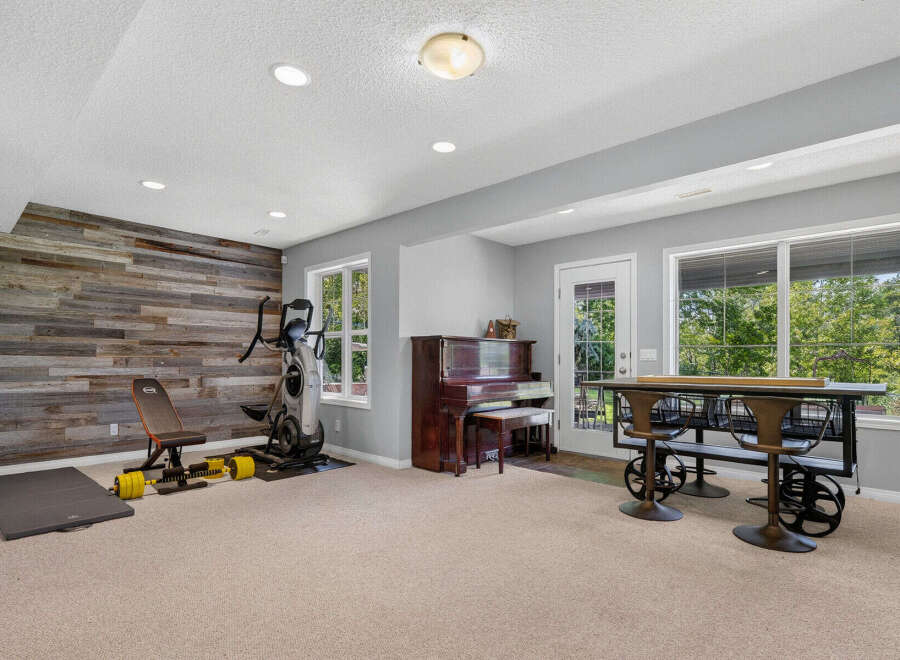 This versatile basement space offers a dedicated home gym area with an elliptical and weight set, perfect for your fitness routine.