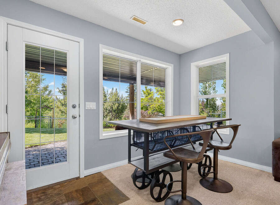 Enjoy indoor-outdoor living with this charming space featuring a stylish bar-height table and stools, perfect for casual dining or entertaining.