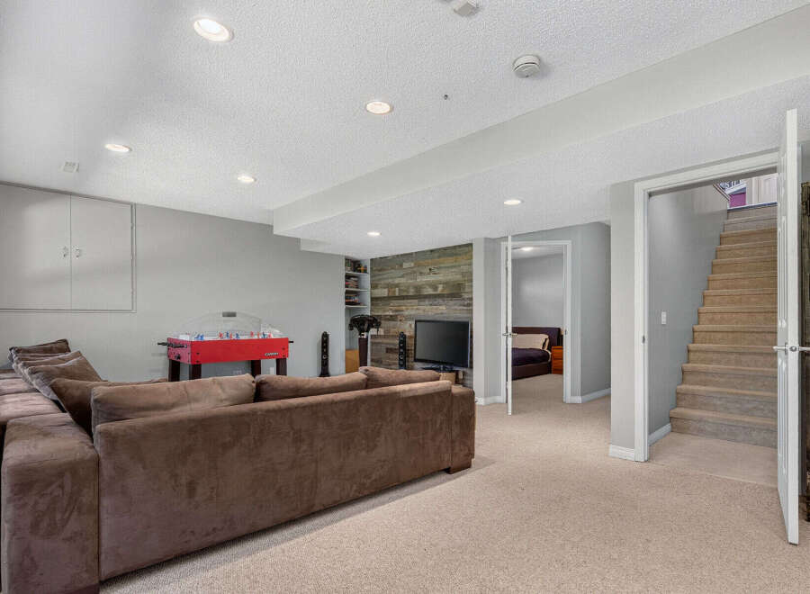 This finished basement offers a spacious entertainment area with a large sectional sofa and a foosball table, perfect for family fun.
