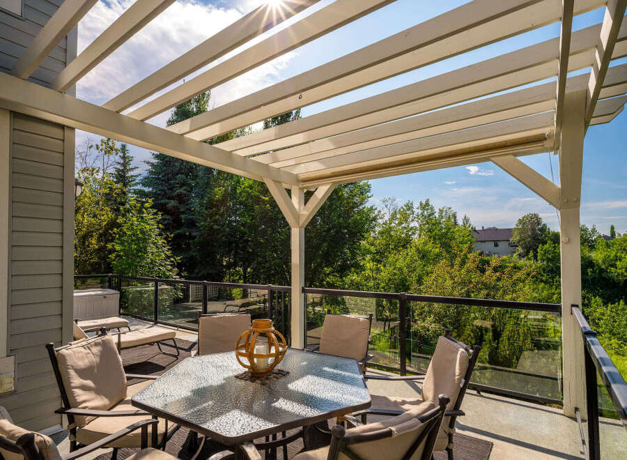 Enjoy outdoor living under this beautiful pergola, offering a shaded dining area with a glass-top table and comfortable seating.